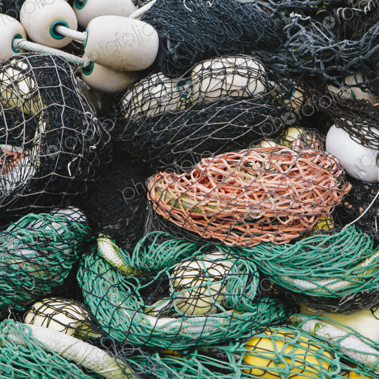 Pile of commercial fishing nets, with white floats, on the quayside at Fisherman's…