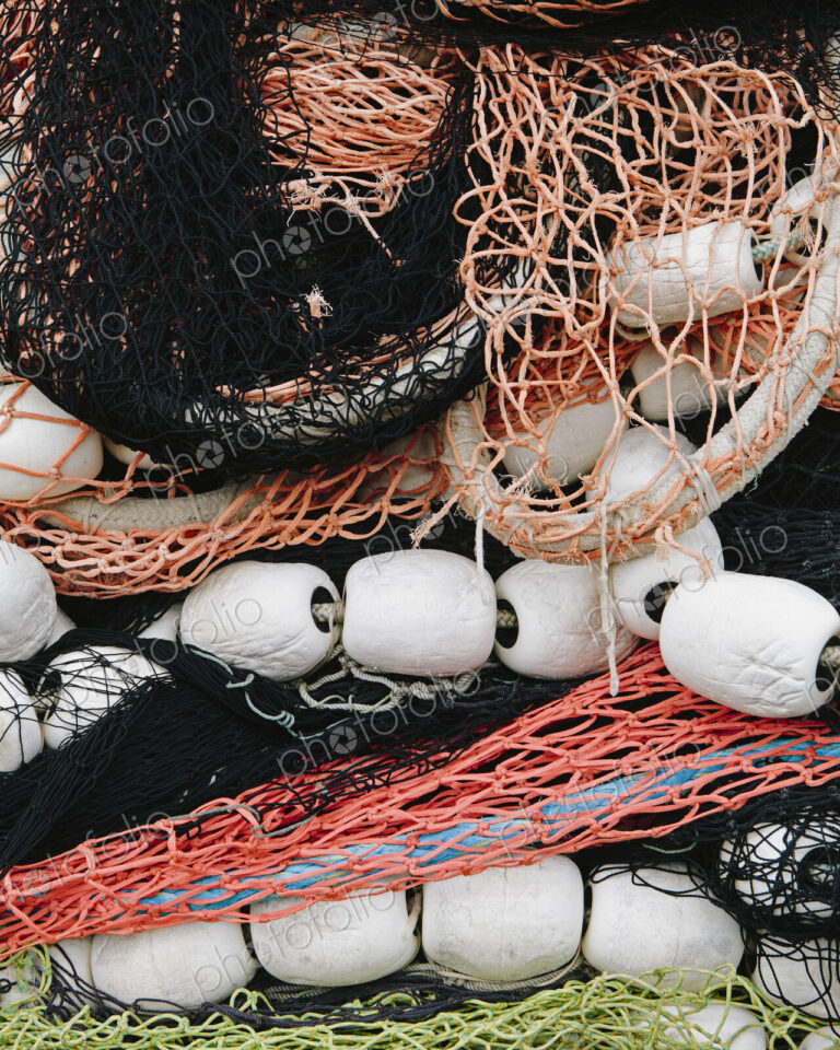 Pile of commercial fishing nets, with white floats, on the quayside at Fisherman's…