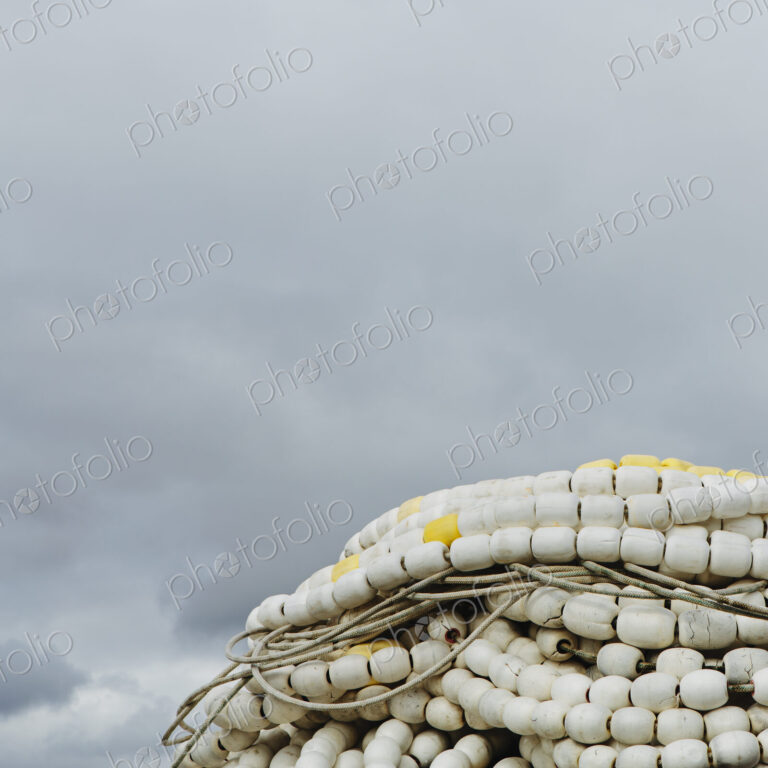 Pile of commercial fishing nets, with white floats, on the quayside at Fisherman's…