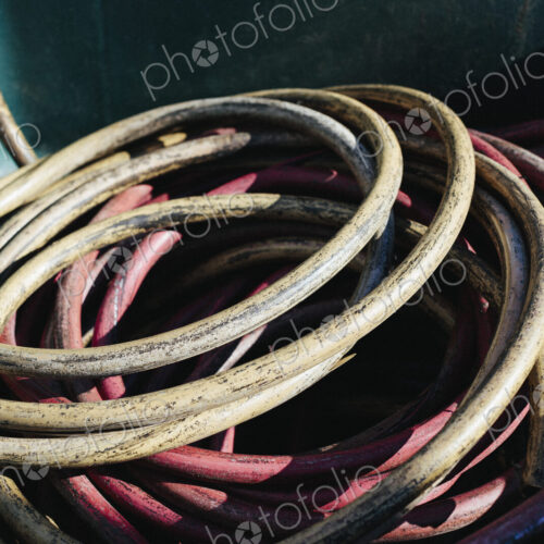 Pile of discarded industrial tubing, coiled in recycling container