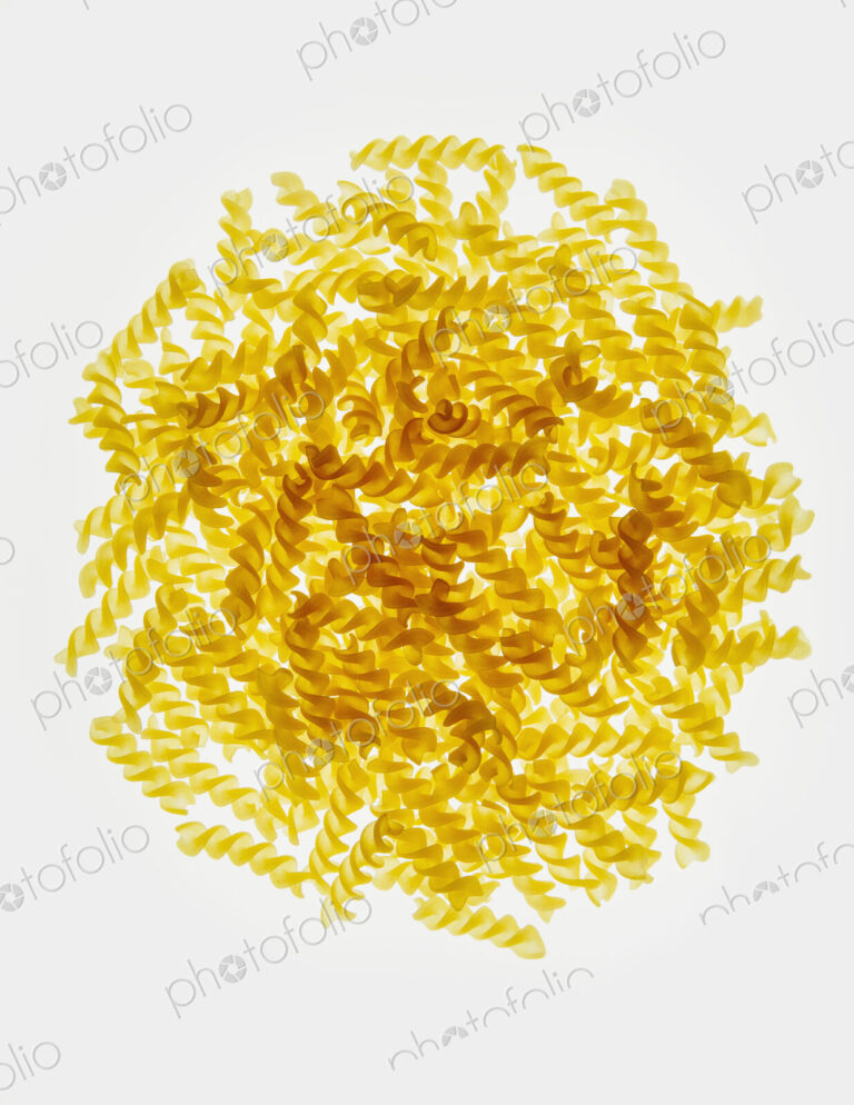 Pile of organic gluten free fusilli pasta spirals, white background