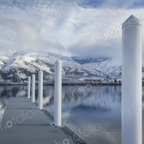 Pillars on dock at lake near snow covered mountain range
