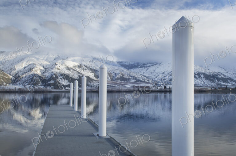 Pillars on dock at lake near snow covered mountain range