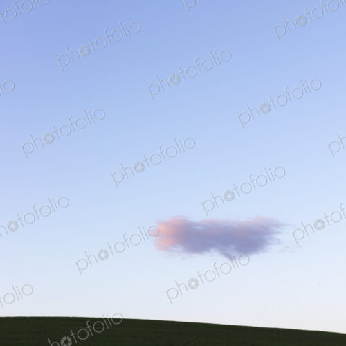 Pink cloud over rolling hills at dusk