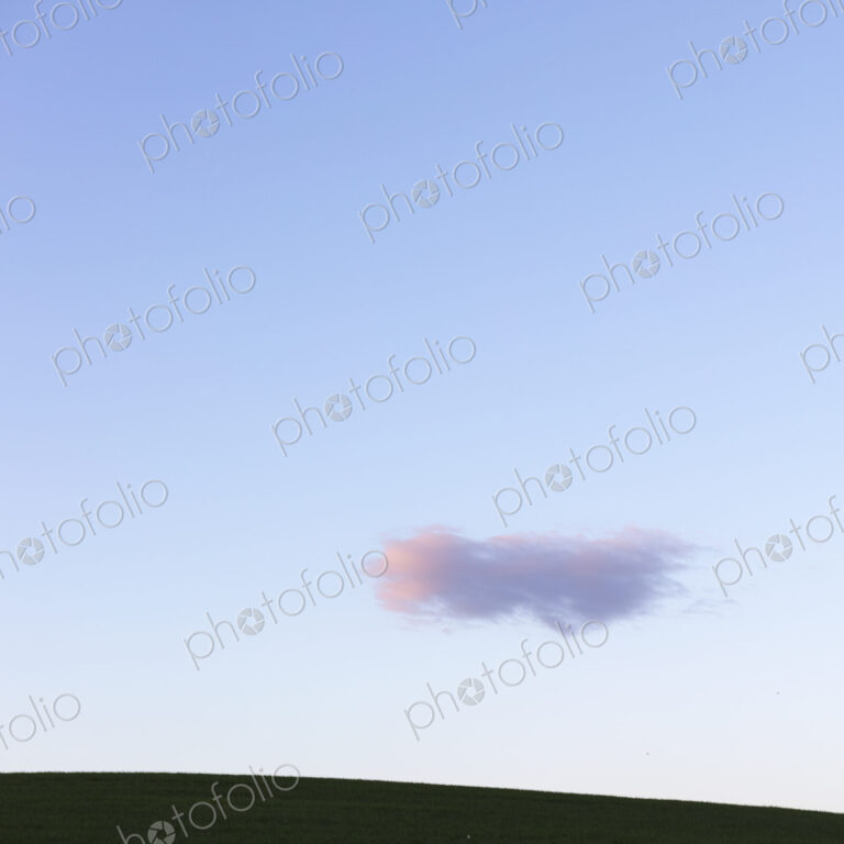 Pink cloud over rolling hills at dusk