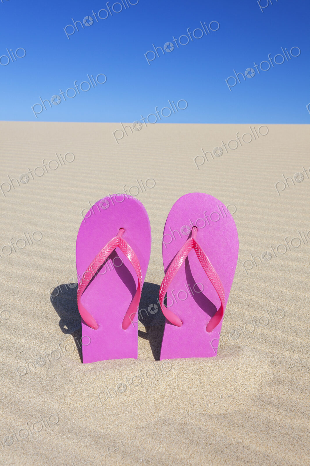 Pink flip flops in sand
