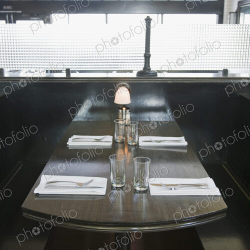 Place settings on empty booth table in restaurant Place settings on empty booth table in restaurant