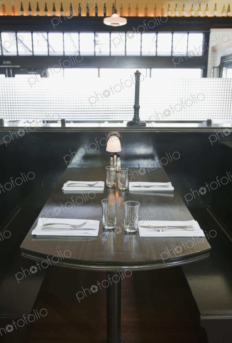 Place settings on empty booth table in restaurant