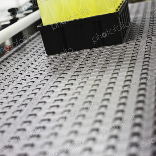 Plastic bottles on conveyor belt in packaging and processing plant.
