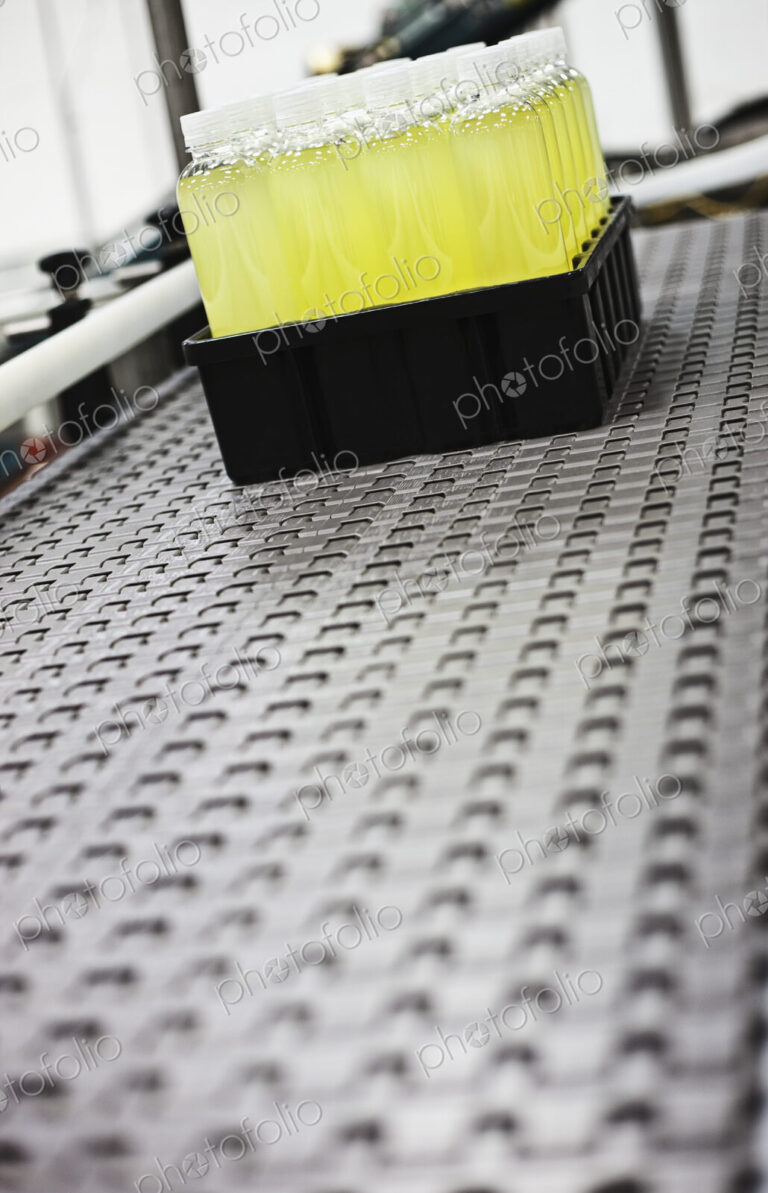 Plastic bottles on conveyor belt in packaging and processing plant.