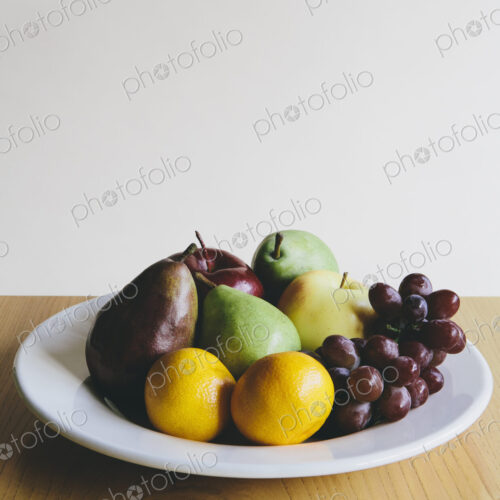Plate of organic fresh fruit (tangerines, grapes, red bartlett pear, green anjou pears…