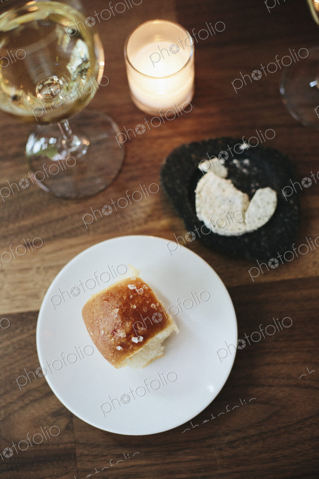 Plate with a bread roll, herb butter and glass of wine at a city restaurant.