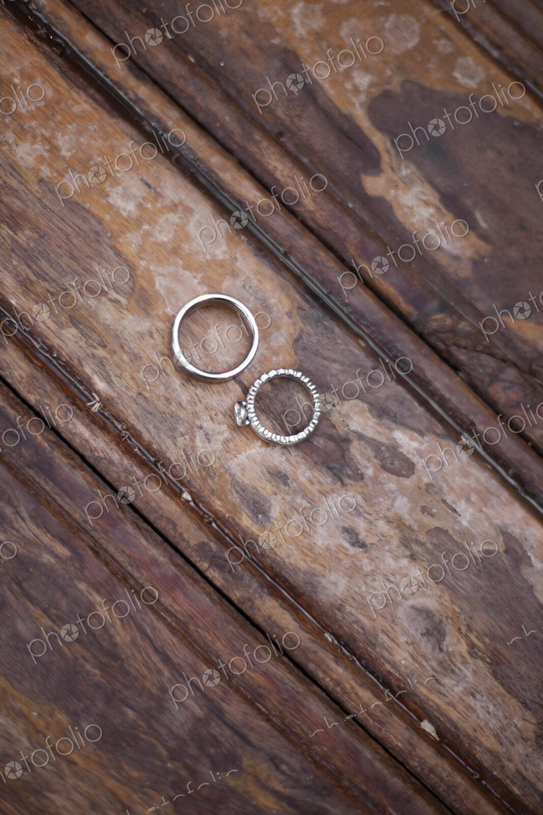 Platinum wedding rings . Two rings on a worn scrubbed stained wooden surface.