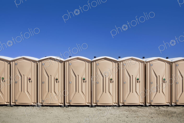Portable toilets at the beach, in a row.