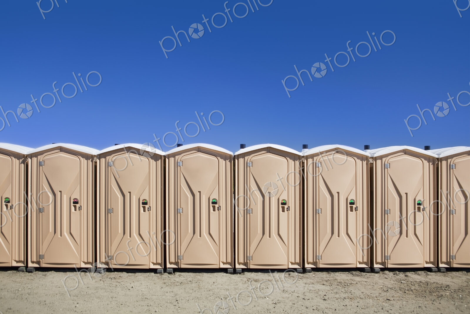 Portable toilets at the beach, in a row.