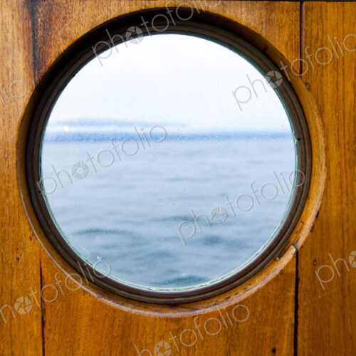 Porthole window on a ferry, with a wooden surround. Porthole window on a ferry, with a wooden surround.