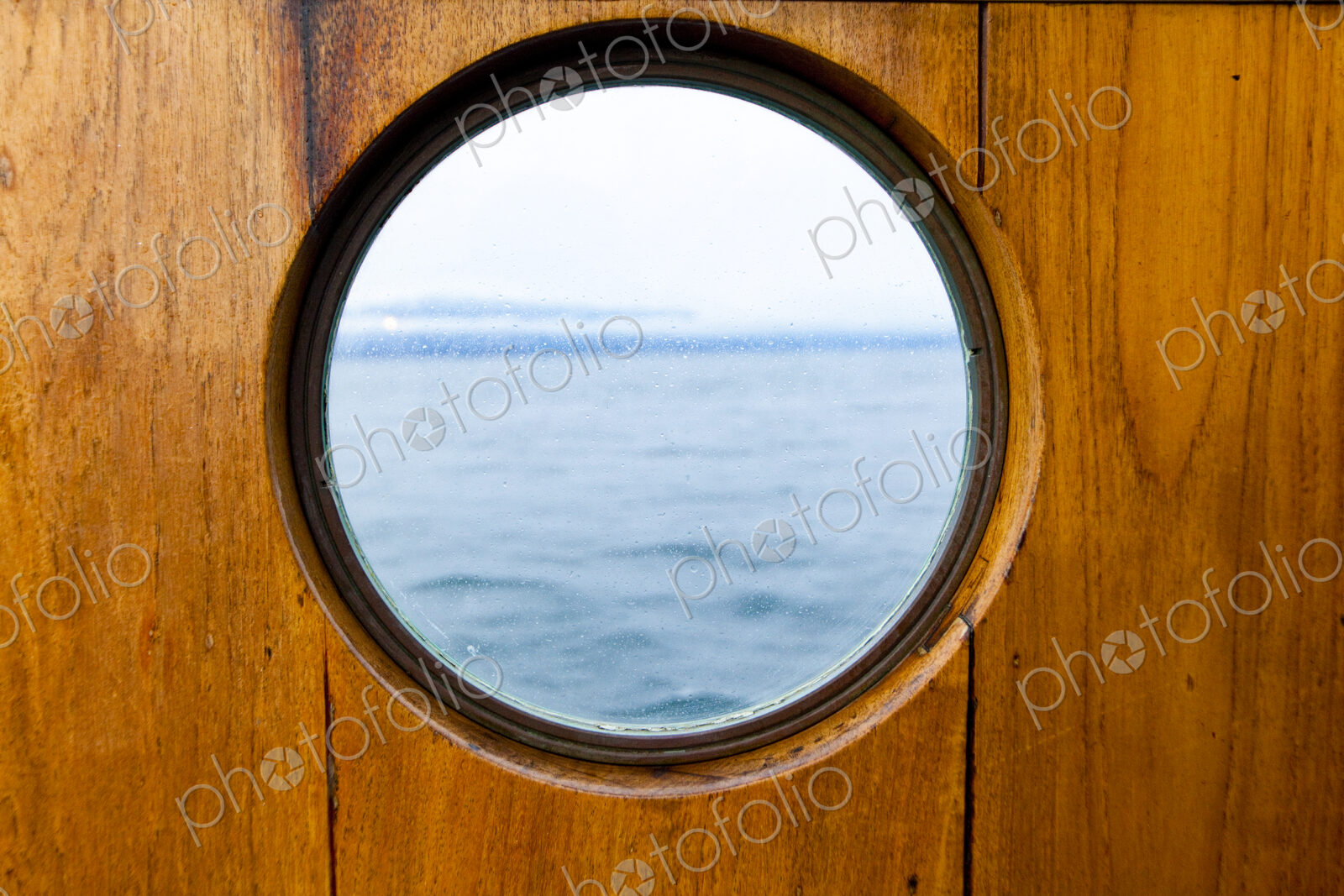 Porthole window on a ferry, with a wooden surround.