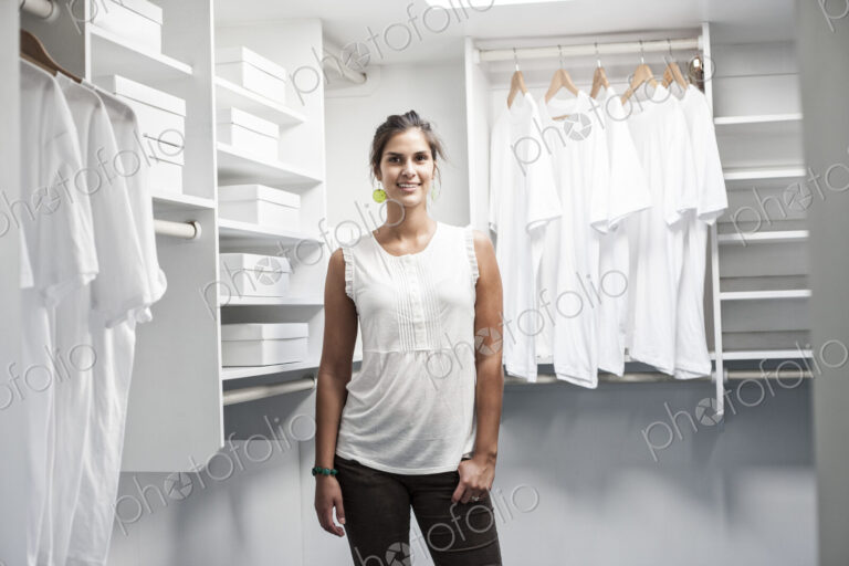 Portrait of HIspanic woman in a closet full of white clothes.