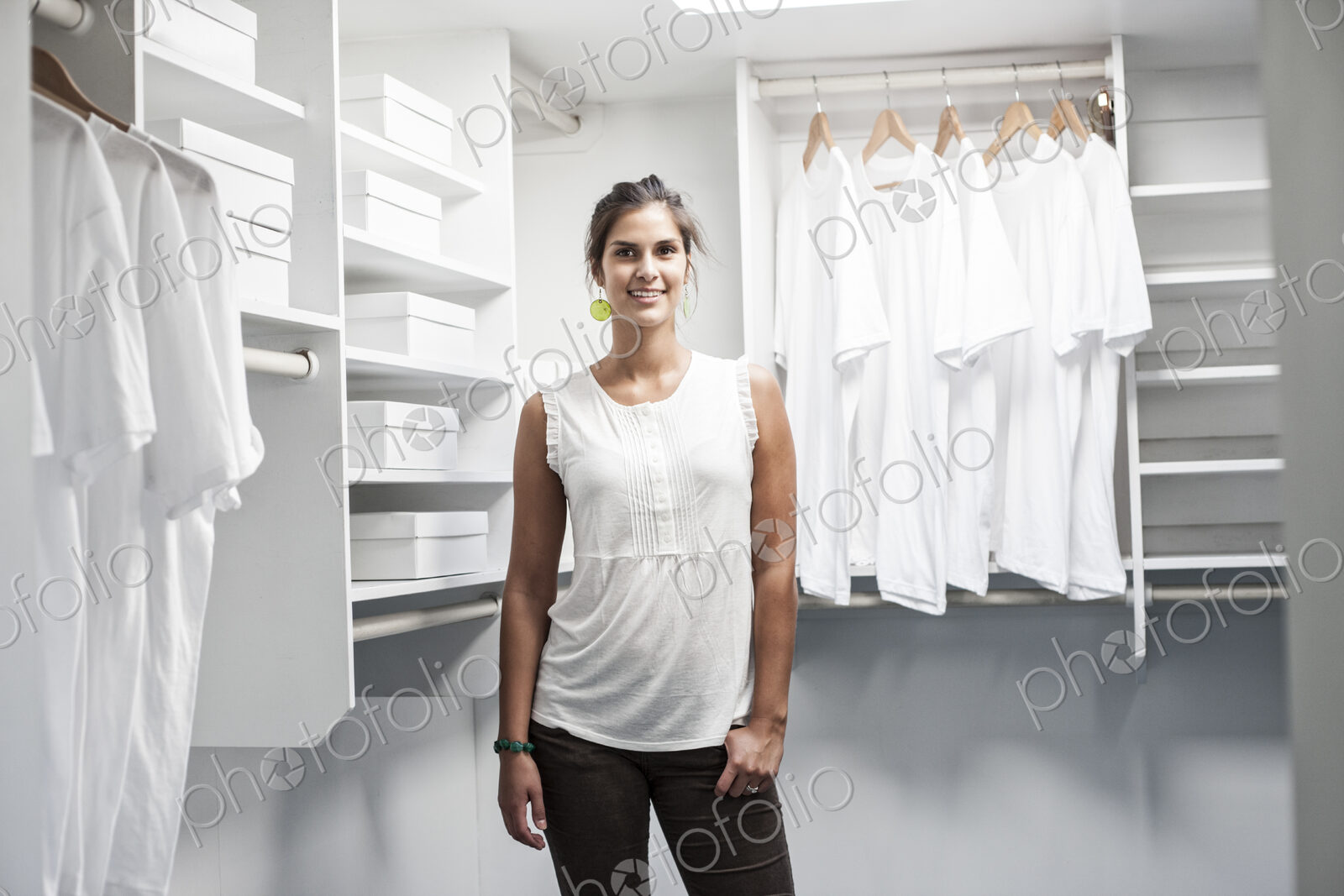 Portrait of HIspanic woman in a closet full of white clothes.