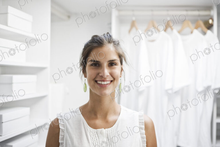 Portrait of HIspanic woman in a closet full of white clothes.