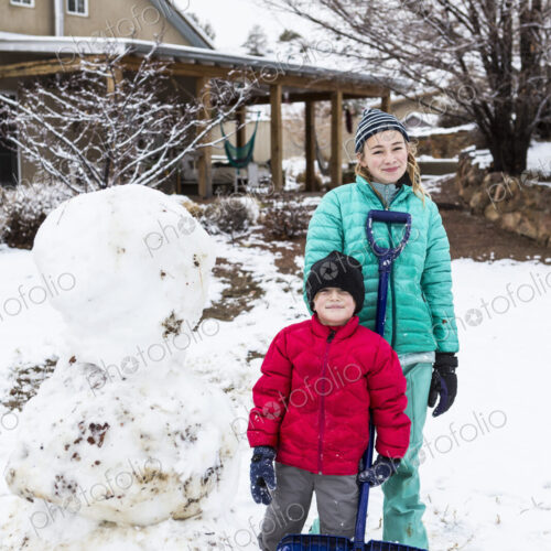 Portrait of Thirteen year old teenage girl and her 6 year old brother posing with snowman Portrait of Thirteen year old teenage girl and her 6 year old brother posing with snowman