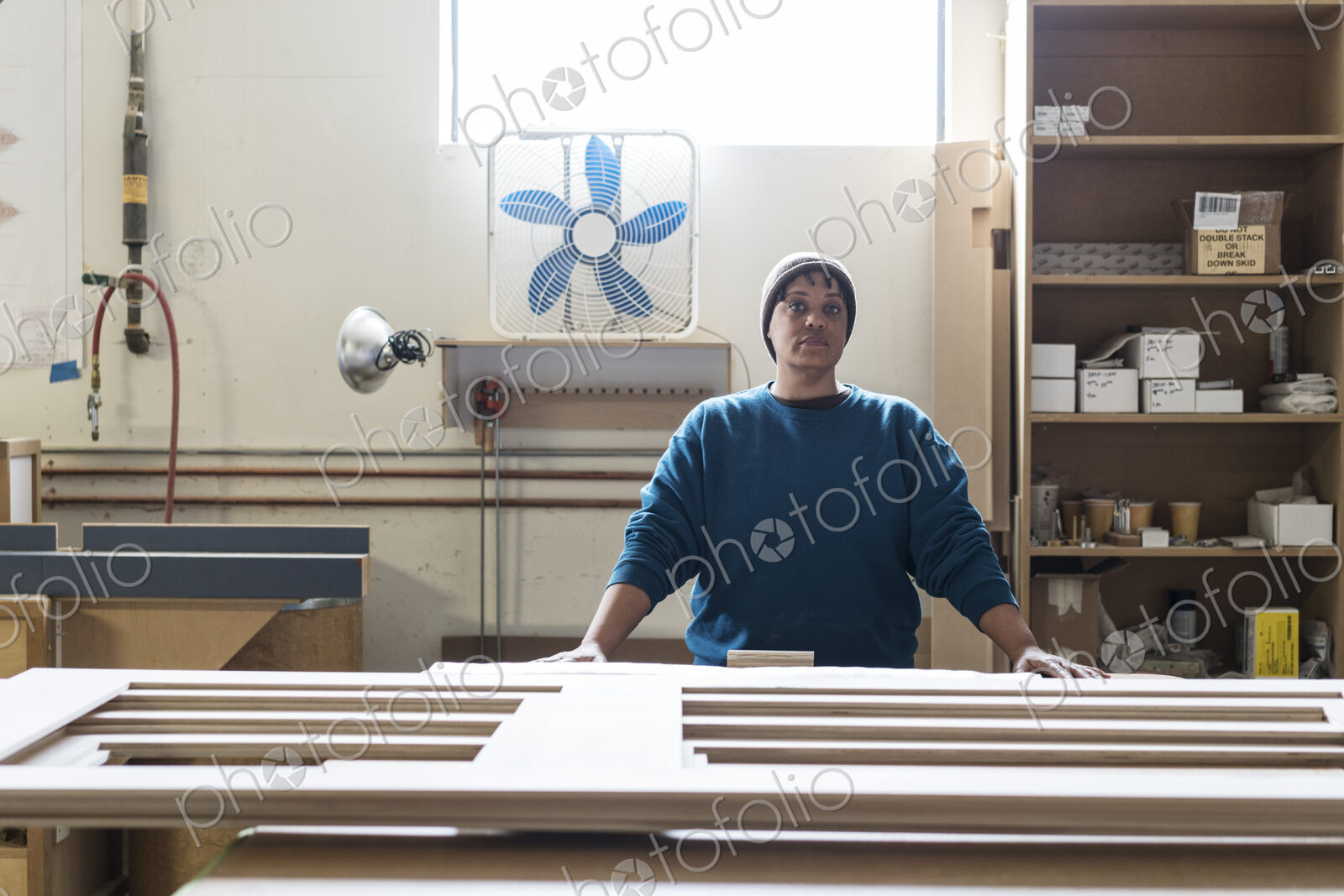 Portrait of a Black woman carpenter in a large woodworking shop.