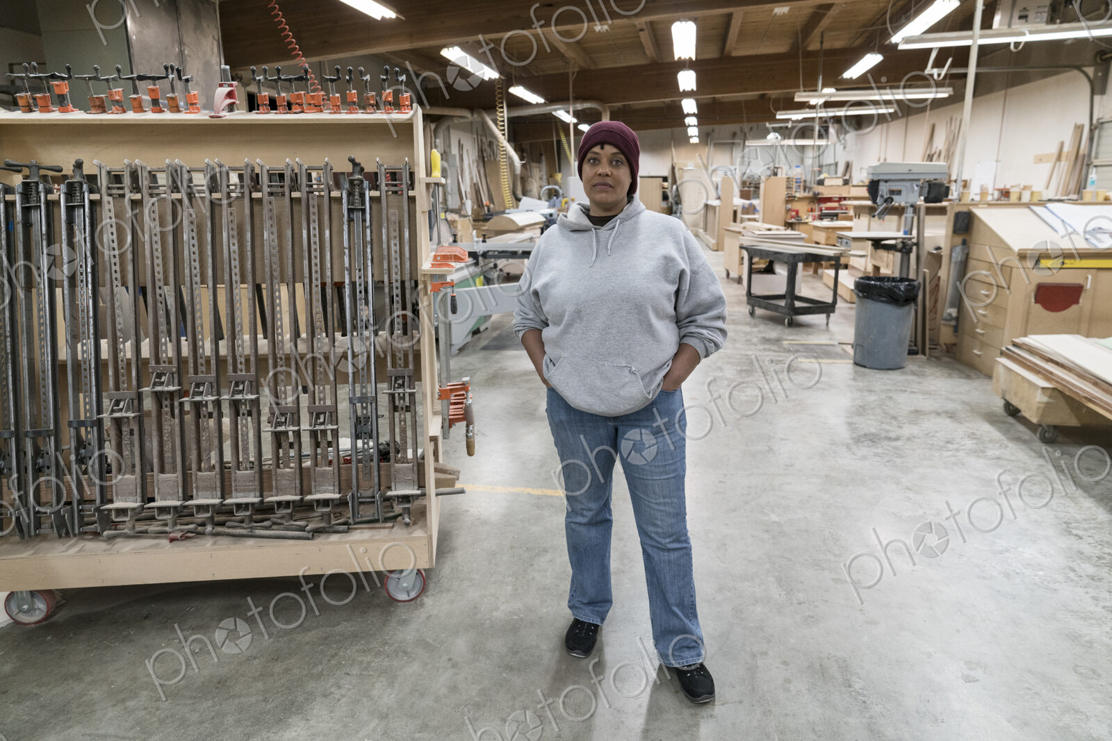 Portrait of a Black woman carpenter in a large woodworking shop.