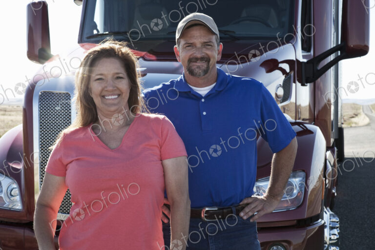 Portrait of a Caucasian husband and wife driving team with their commercial truck.