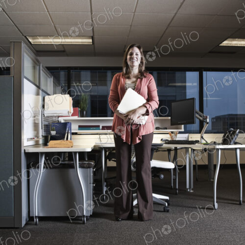Portrait of a Caucasian woman standing in her cubicle office space. Portrait of a Caucasian woman standing in her cubicle office space.