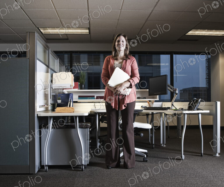 Portrait of a Caucasian woman standing in her cubicle office space.
