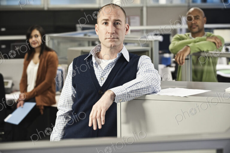 Portrait of a Mixed Race team of three people in an office cubicle setting'