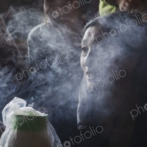 Portrait of a Tibetan Woman in a monastery, face wreathed in smoke.