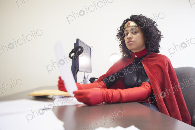 Portrait of a black businesswoman office super hero sitting at her office computer.