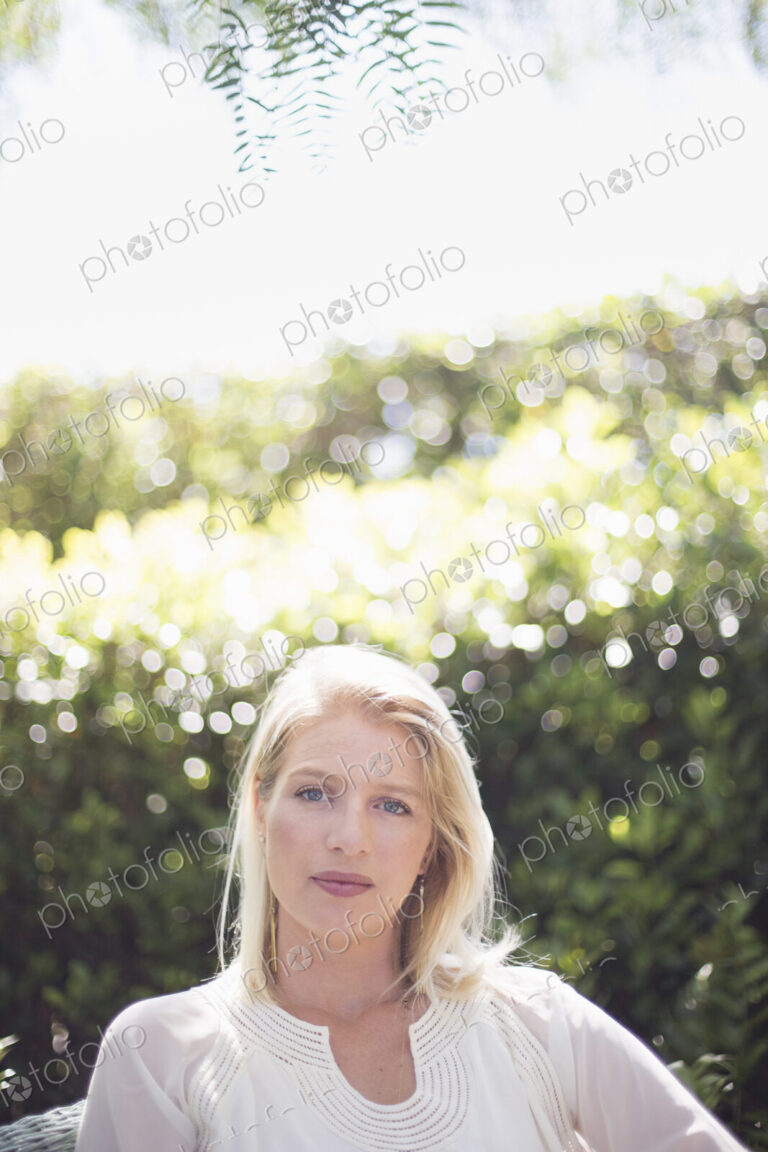 Portrait of a blond woman standing in a garden.