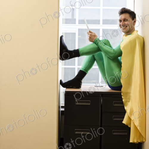 Portrait of a caucasian businessman office super hero sitting in a window using his phone. Portrait of a caucasian businessman office super hero sitting in a window using his phone.