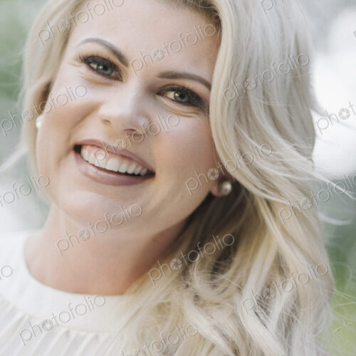 Portrait of a pregnant woman with long blond hair in a garden.