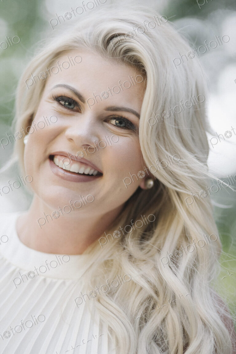 Portrait of a pregnant woman with long blond hair in a garden.