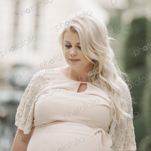 Portrait of a pregnant woman with long blond hair in a garden.