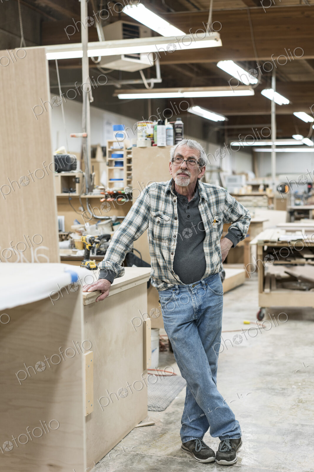 Portrait of a senior Caucasian carpenter in a large woodworking shoop.