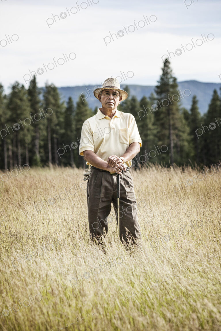 Portrait of a senior golfer standing in the heavy rough of a golf course.
