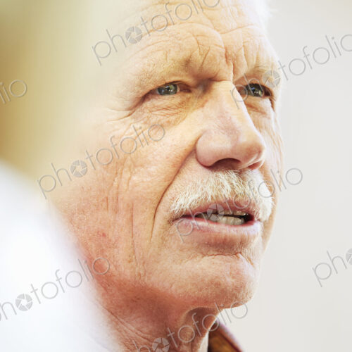 Portrait of a senior man with moustache sitting outdoors.