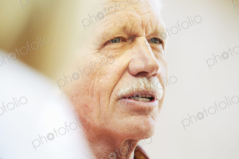 Portrait of a senior man with moustache sitting outdoors.