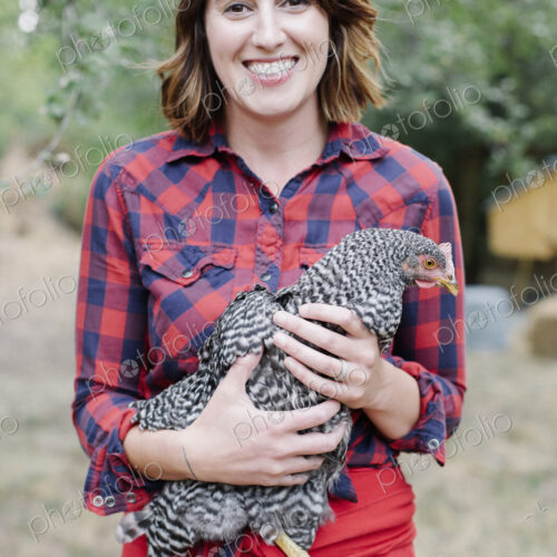 Portrait of a smiling woman holding a grey specked hen. Portrait of a smiling woman holding a grey specked hen.