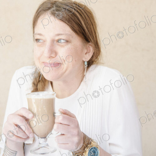 Portrait of a smiling woman with auburn hair holding a cafe latte. Portrait of a smiling woman with auburn hair holding a cafe latte.