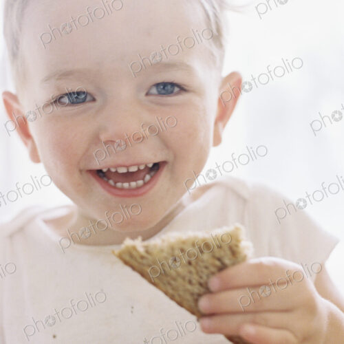 Portrait of a smiling young boy eating a sandwich.