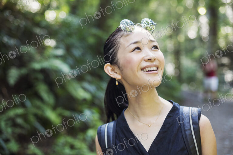 Portrait of a smiling young woman standing in a forest.