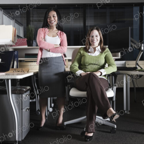 Portrait of a team of Caucasian and Asian business women in an office cubicle space. Portrait of a team of Caucasian and Asian business women in an office cubicle space.
