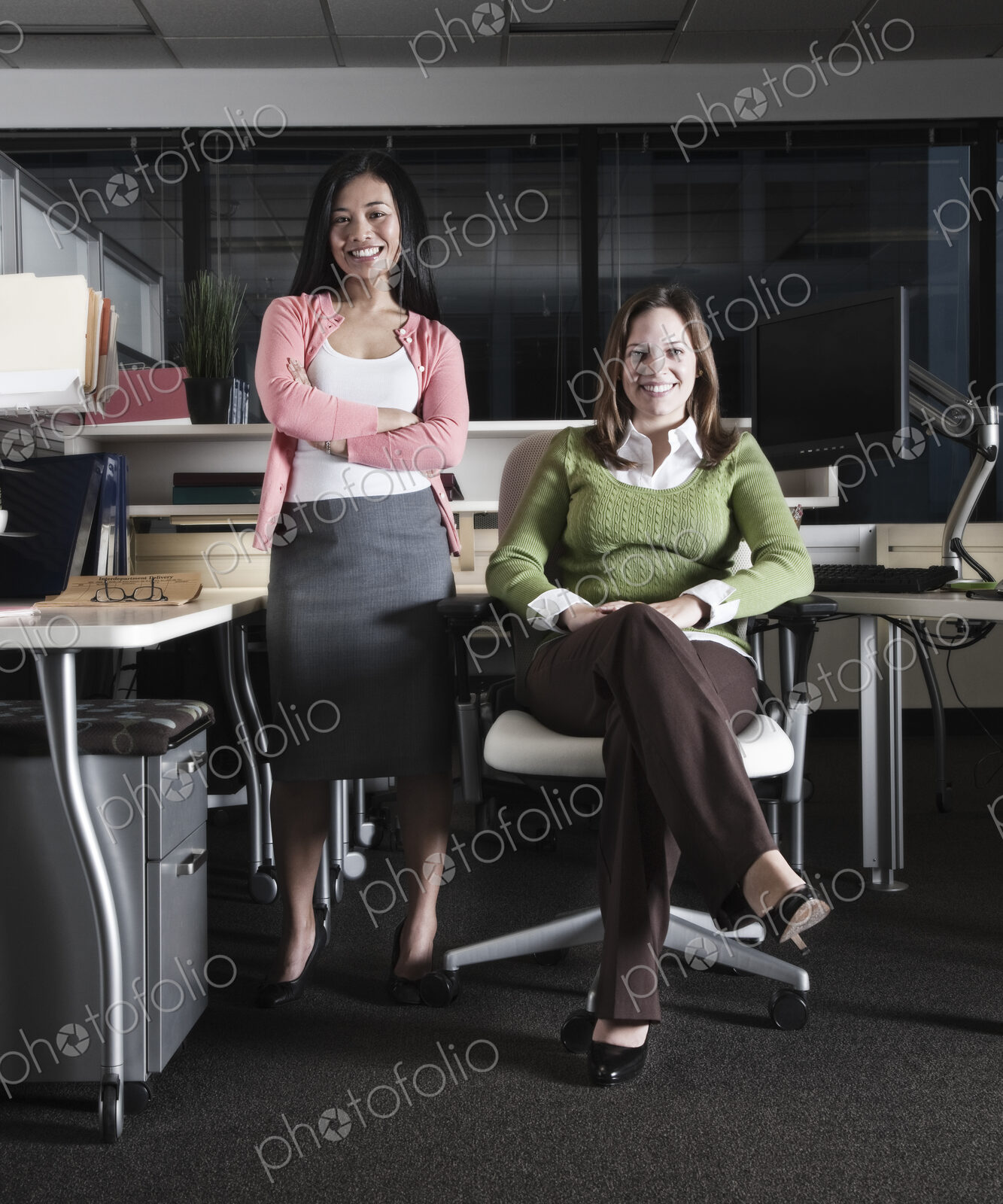 Portrait of a team of Caucasian and Asian business women in an office cubicle space.