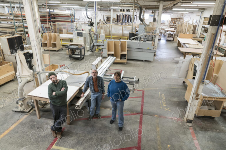 Portrait of a team of three mixed race carpenters in a large woodworking factory.