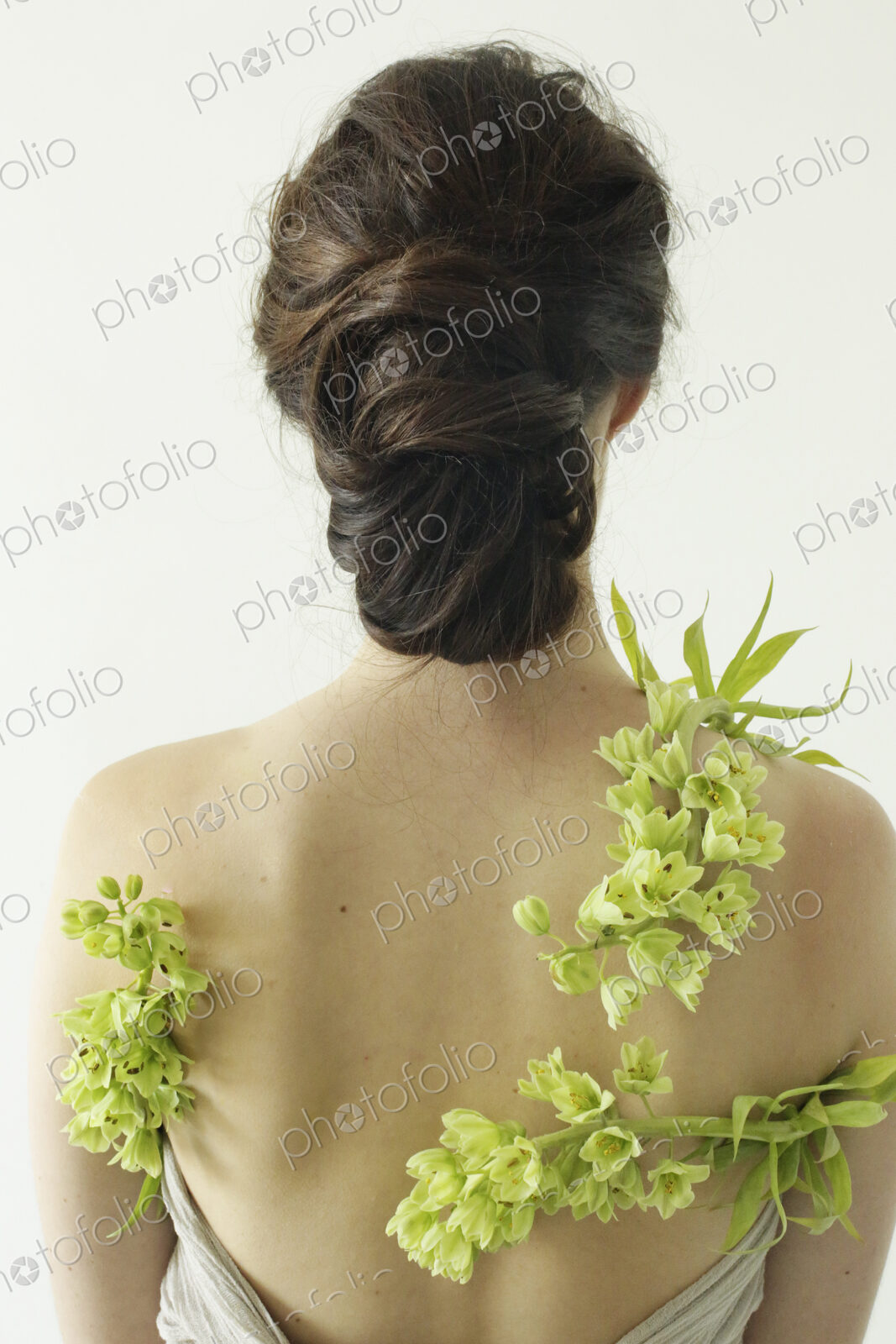 Portrait of a woman with brown hair tied in an elegant bun, wearing a dress with a…